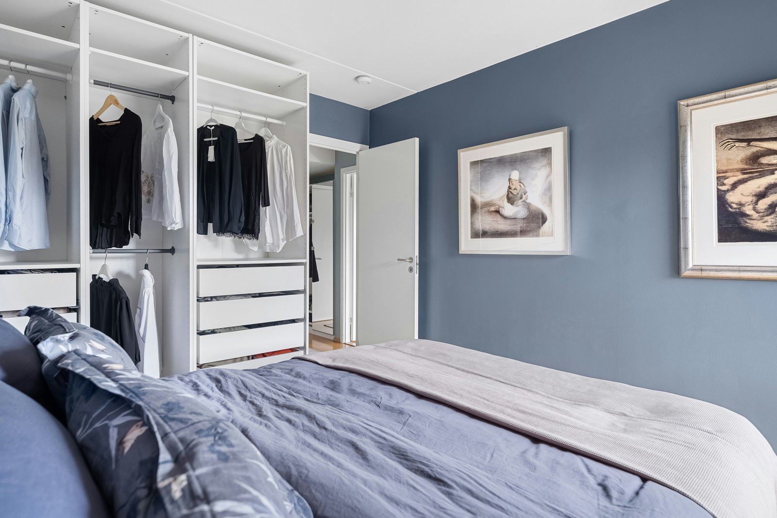 Innenraum eines Holzkleiderschranks mit Kleidung auf Bügeln