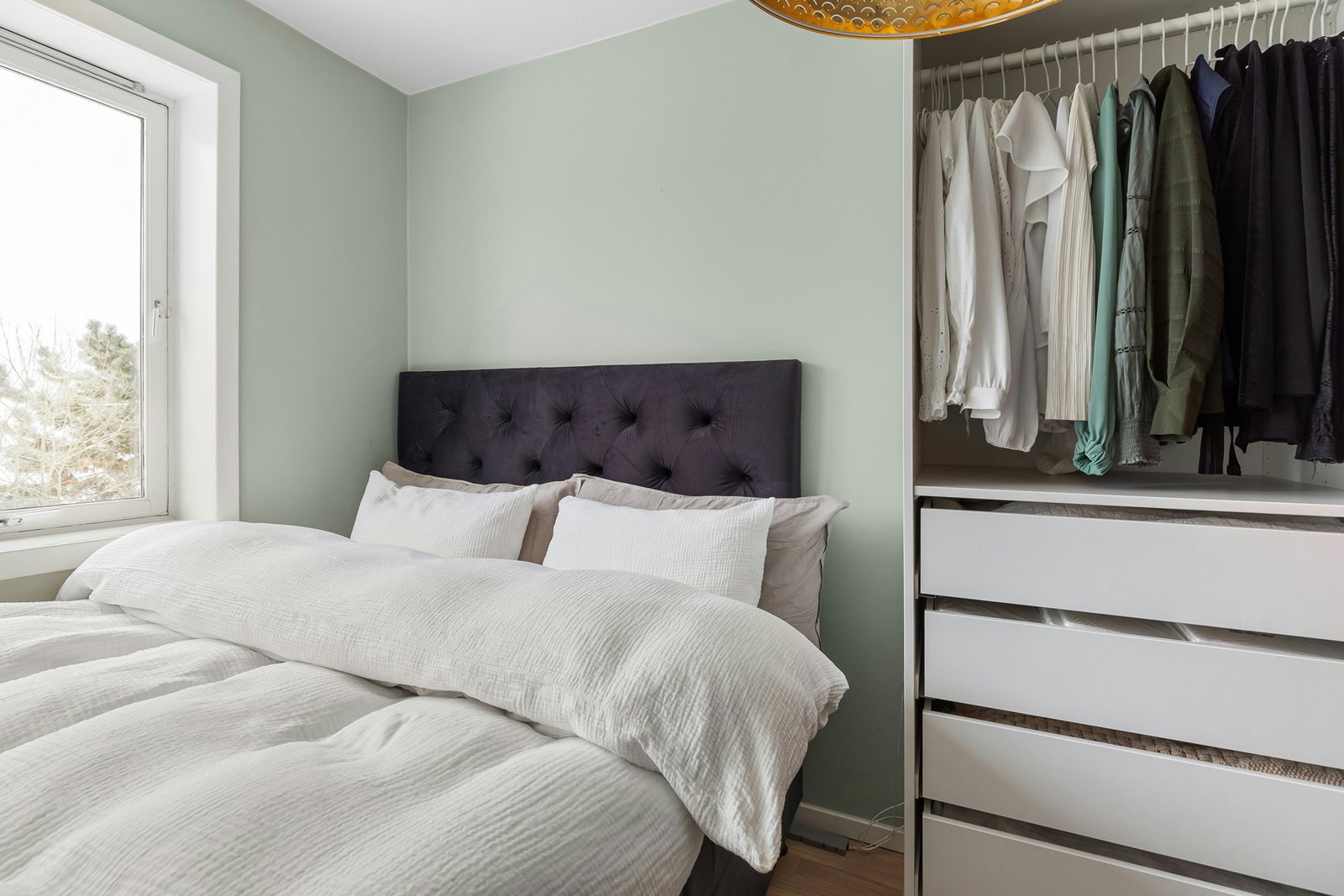 Innenraum eines Kleiderschranks mit Kleidung auf Bügeln und Regalböden